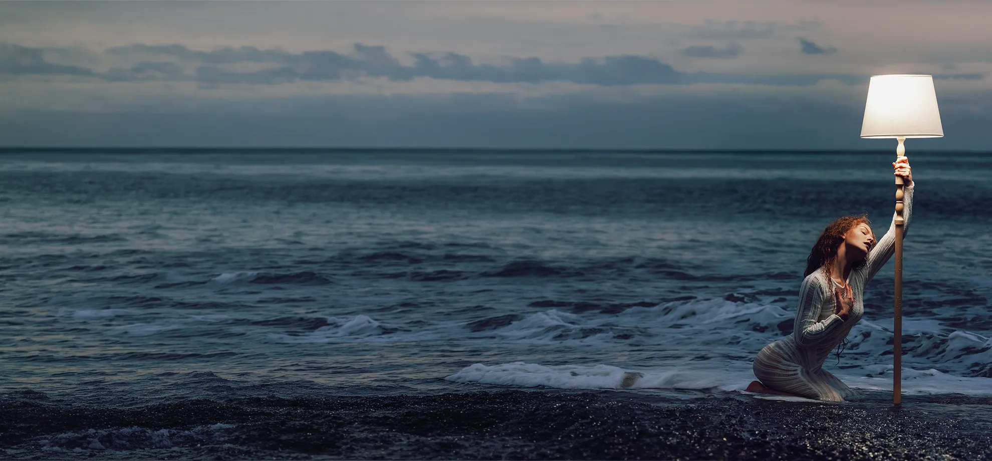 Aleksandra in a cold ocean scene, lit by a single warm lamp